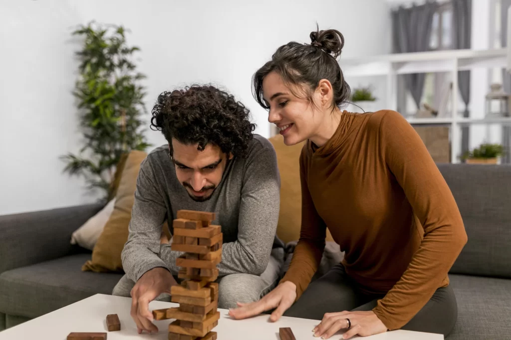 Couple playing a board game in their living room – a cozy and fun at-home date night idea.