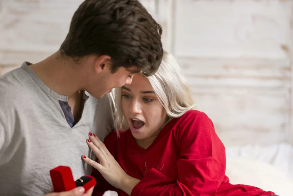 A man or woman holding a small ring box