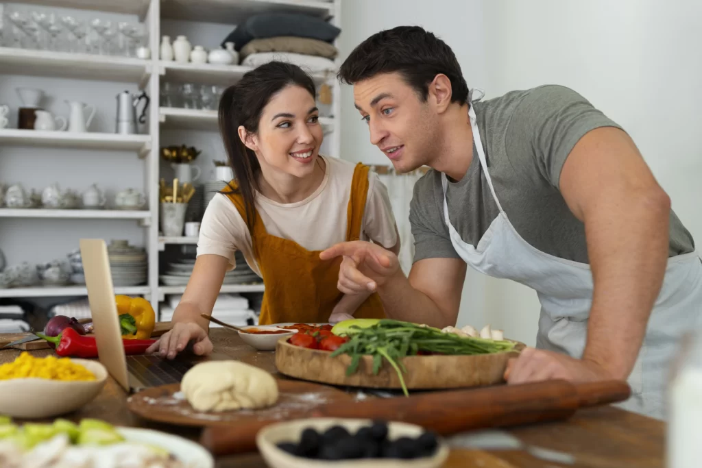 Happy couple cooking together in a home kitchen, representing cute and surprise date night ideas to try together.