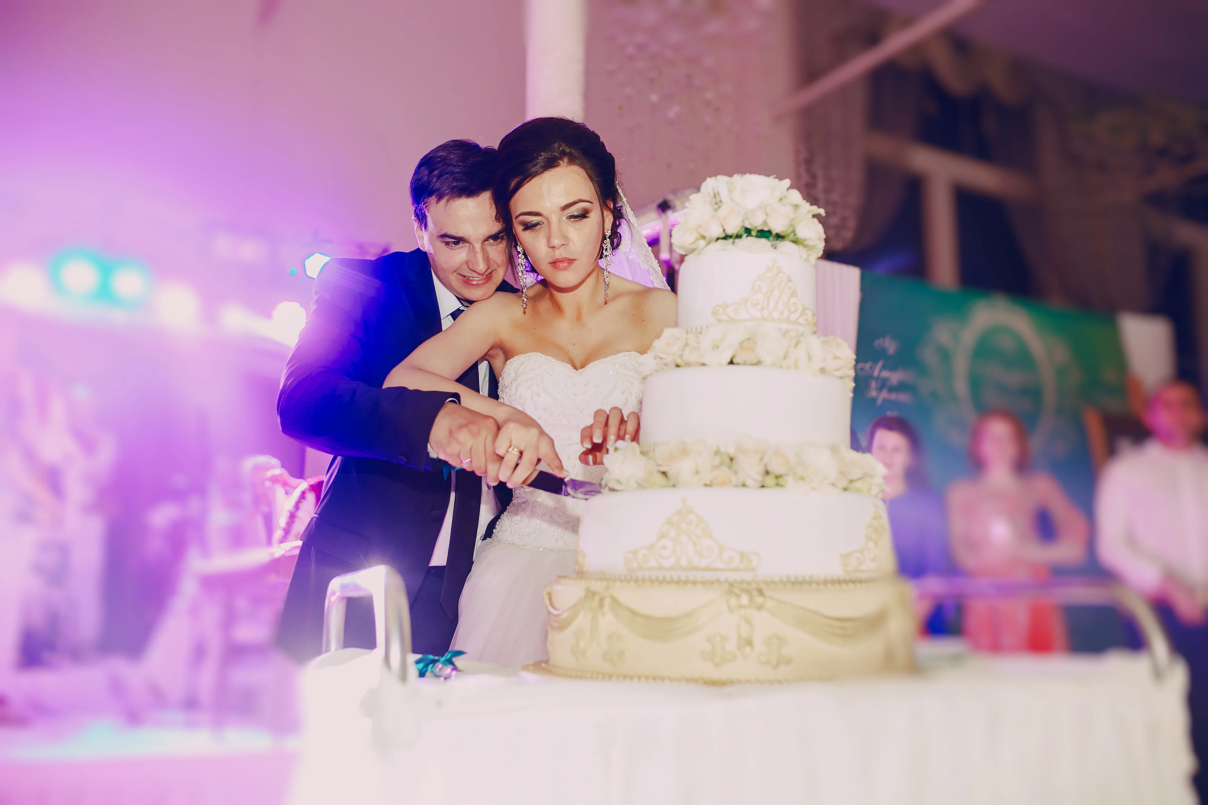 A bride and groom enter a stunning indoor wedding reception with cheering guests, glowing string lights, and a neon sign that says “Forever Starts Here.”