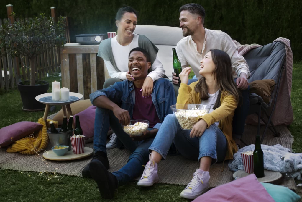 Outdoor movie night setup with a projector and friends watching a film under the stars