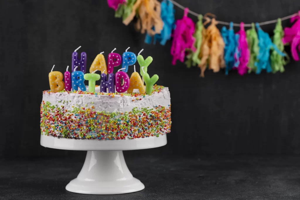 Birthday cake surrounded by party snacks and desserts on a decorated table