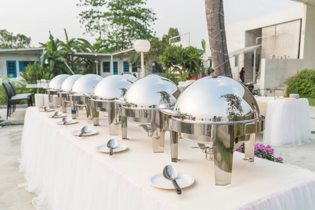 Outdoor catering buffet with food stations and staff serving guests at a sunny event