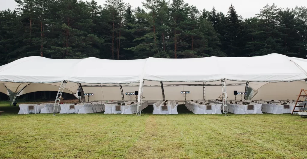 Event tents and umbrellas protecting guests during unexpected rain at an outdoor party